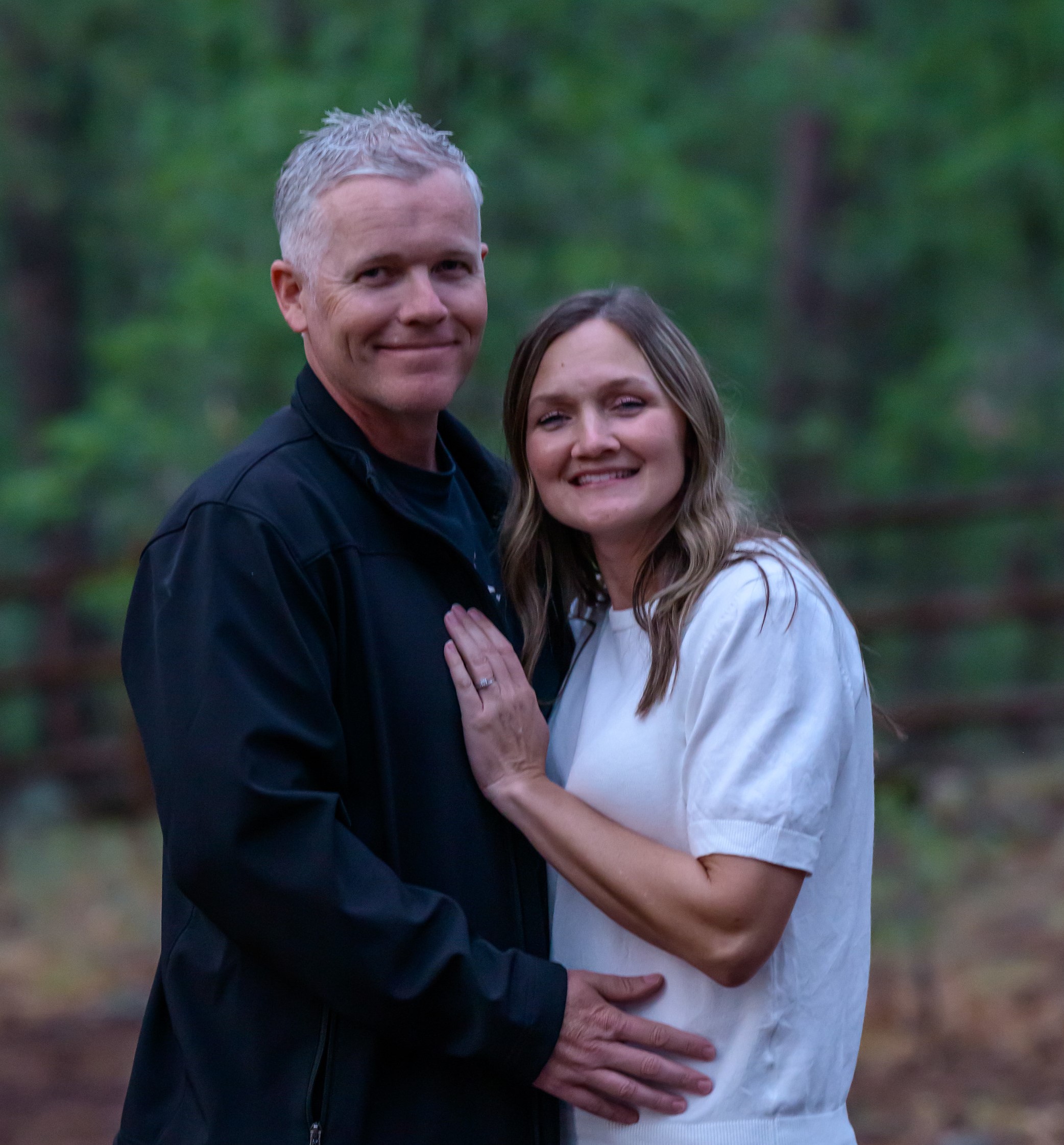 Three founders, a man and a woman in their 30s, sitting together on a sunlit porch, both wearing faith-themed shirts. They hold hands, smiling with gratitude, a car key resting between them, symbolizing their survival. The scene radiates hope and unity.