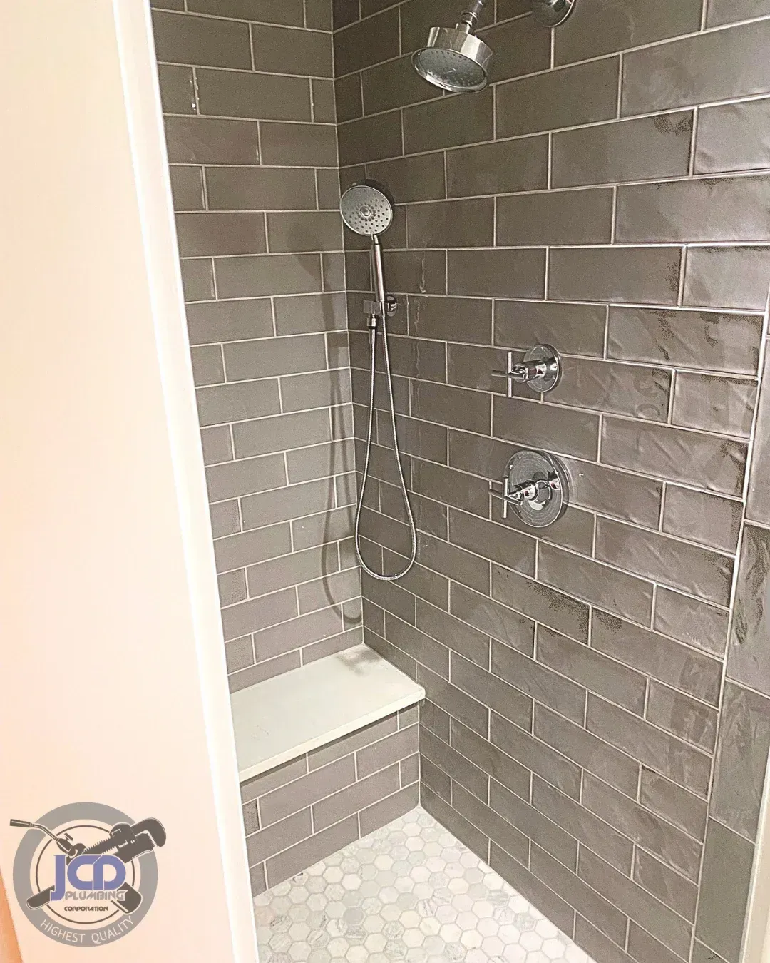 Residential shower plumbing installation with tiled walls and integrated bench in a modern bathroom remodel