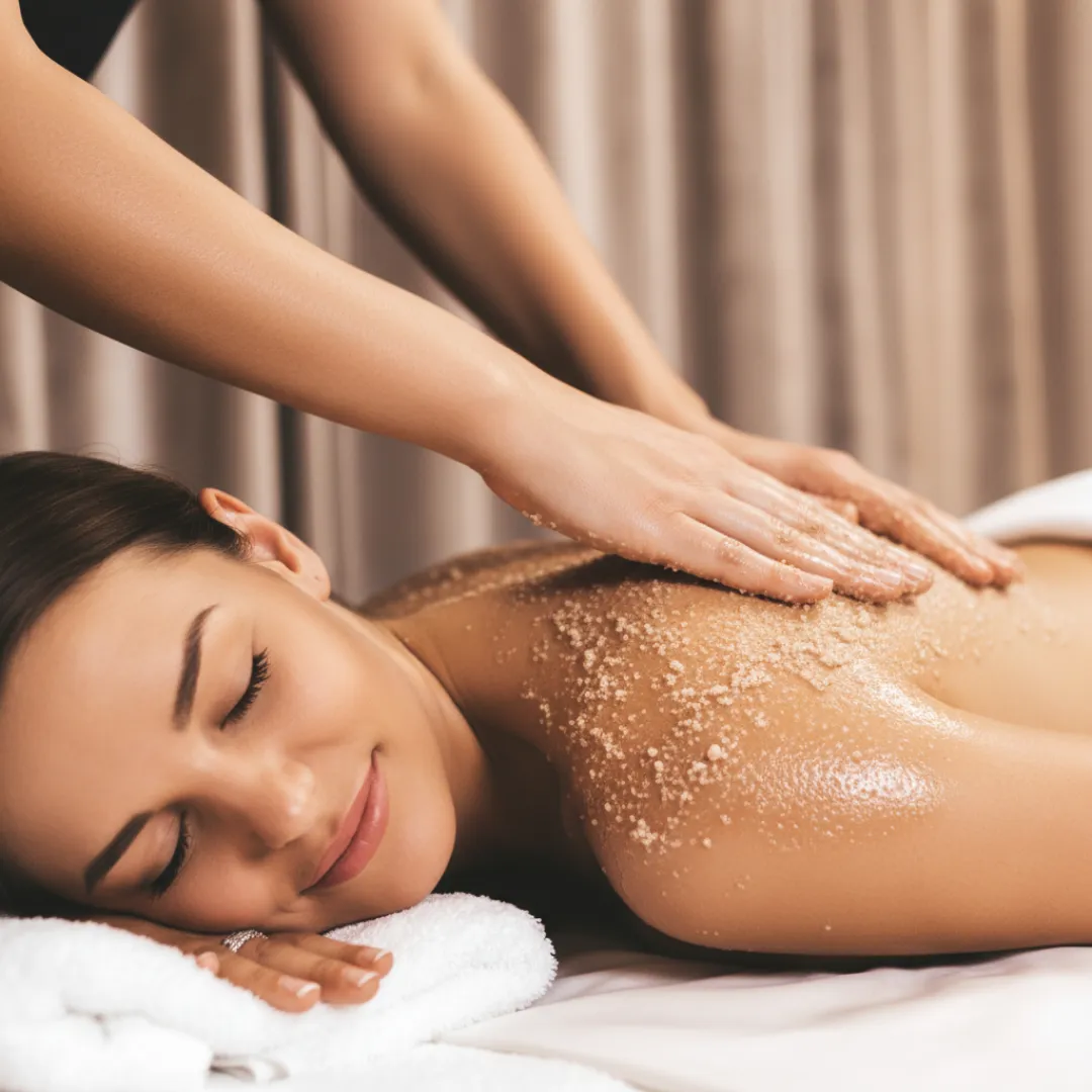 Therapist applying body scrub exfoliation to smooth skin