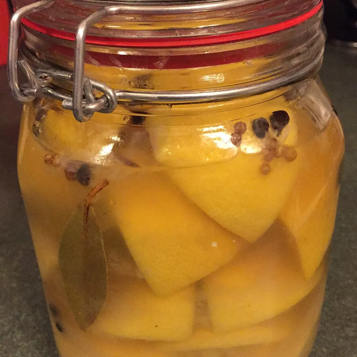 Swing-top jar of preserved lemons with peppercorns and a bay leaf