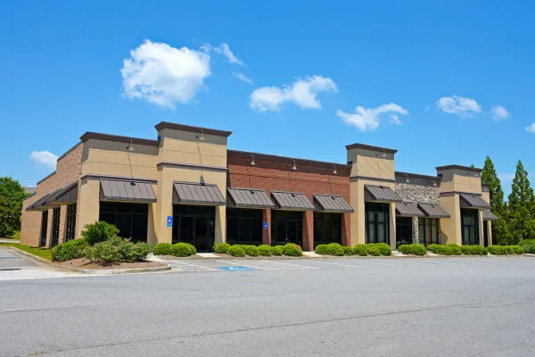 Exterior of a commercial building with large windows and parking lot under clear sky.