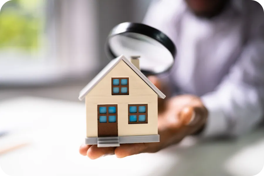 Home inspector in Charlotte, NC examining house model with magnifying glass during pre-listing inspection | Charlotte Home Inspector Pros