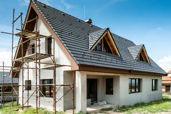Partially built house with exposed roof framing and scaffolding during construction inspection.