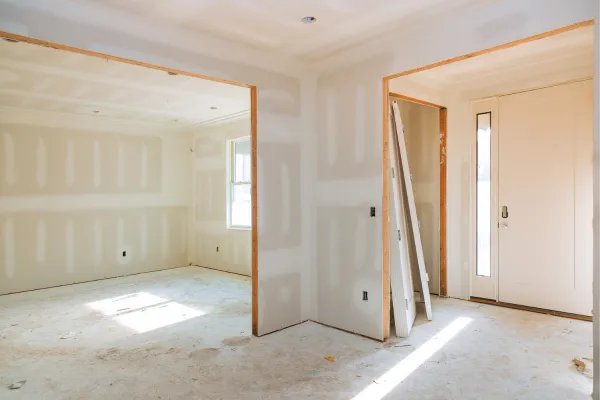 Interior view of a house under construction with open framing and drywall partially installed.