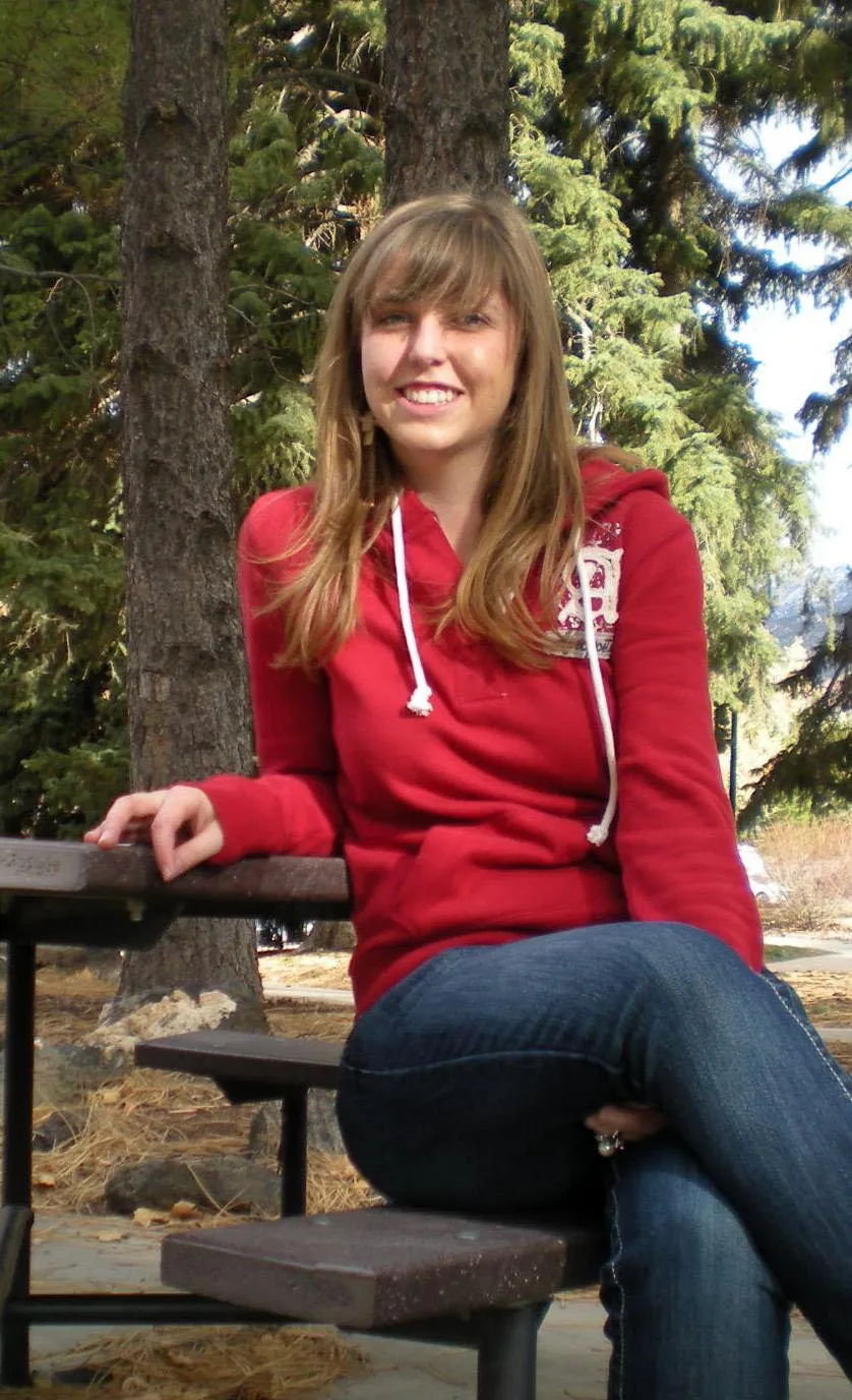 Tara sitting on a picnic table benchh on SUU campus