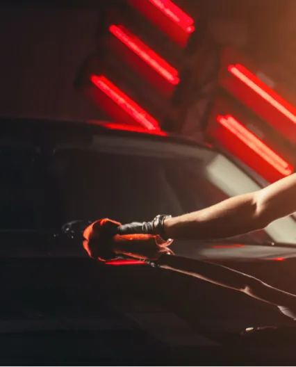 A person wiping the hood of a black car