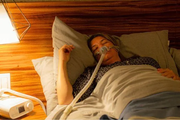 Woman in bed using a CPAP for a sleep disorder