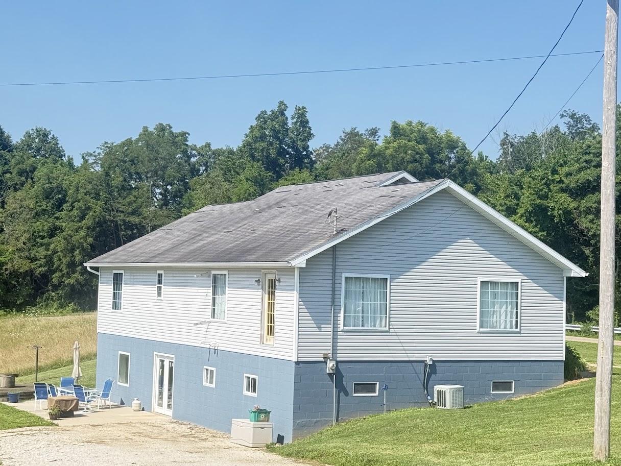 Before image of the house with an older, lighter gray/brown roof showing signs of wear.