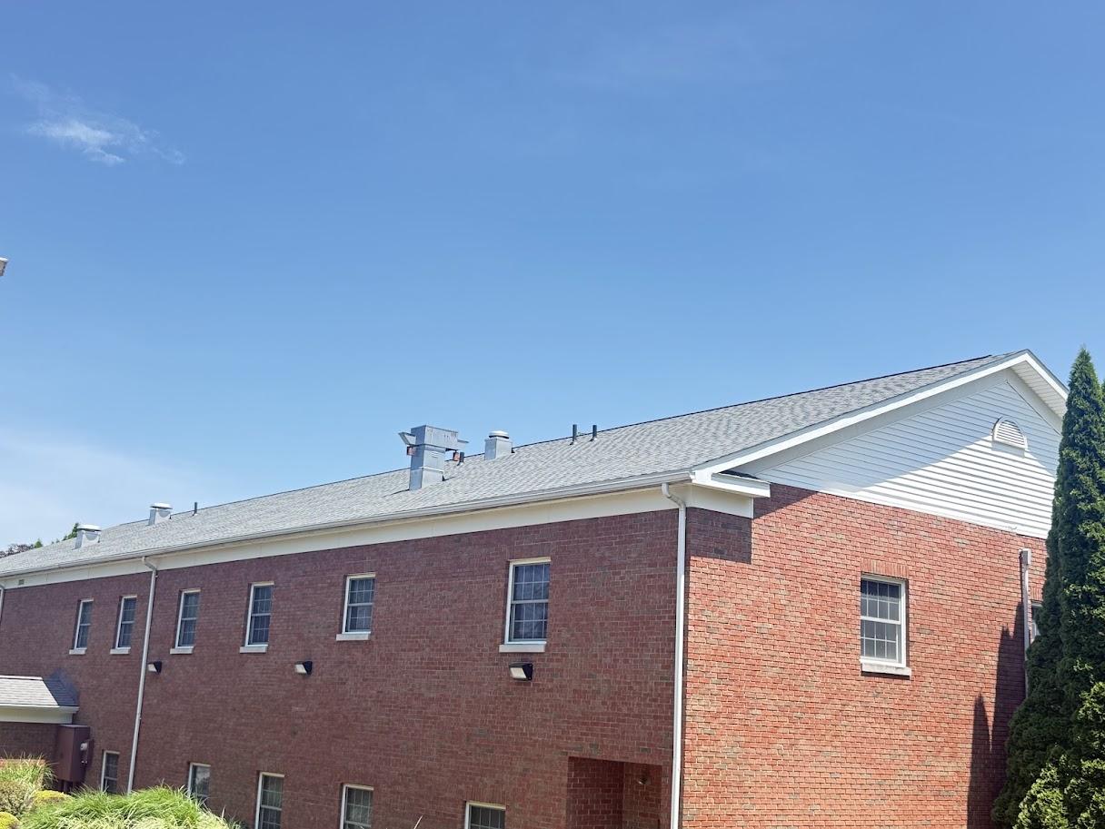 After image of the same house with a brand new, dark gray shingle roof.