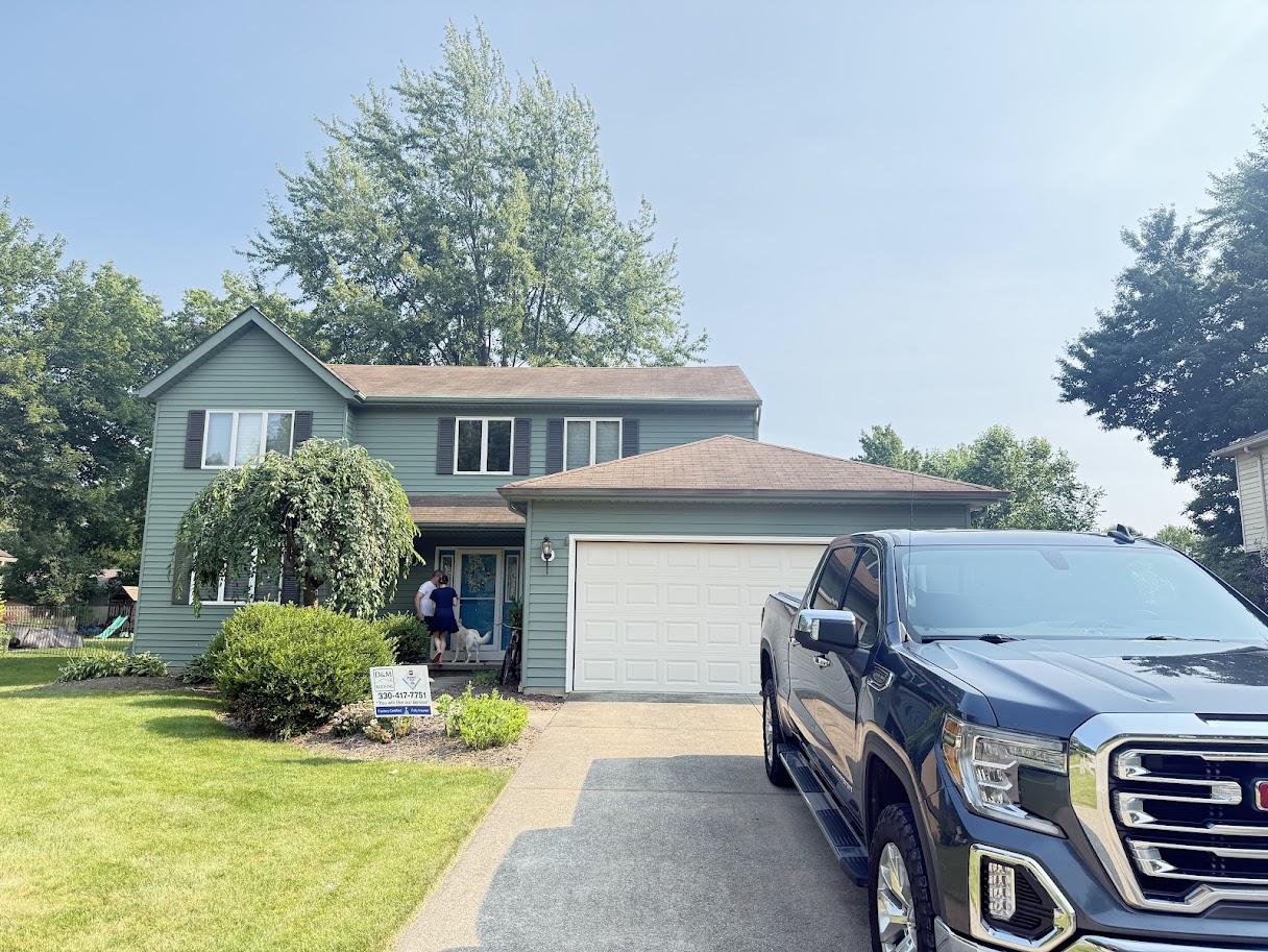 Before image of the house with an older, lighter gray/brown roof showing signs of wear.