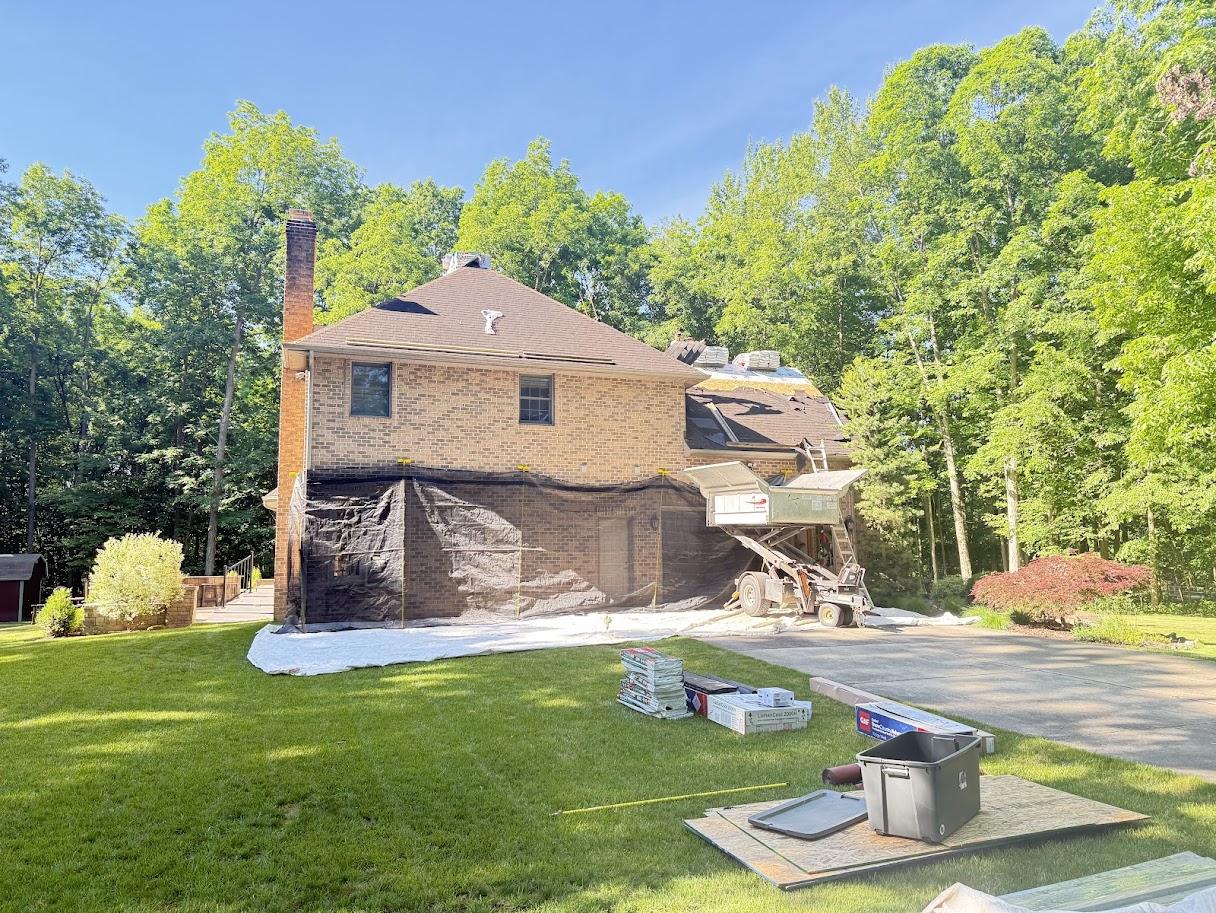 Before image of the house with an older, lighter gray/brown roof showing signs of wear.