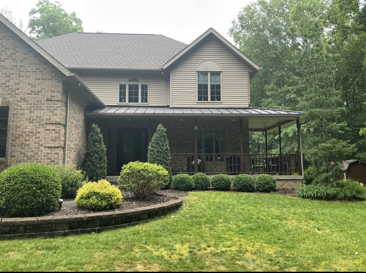 After image of the same house with a brand new, dark gray shingle roof.
