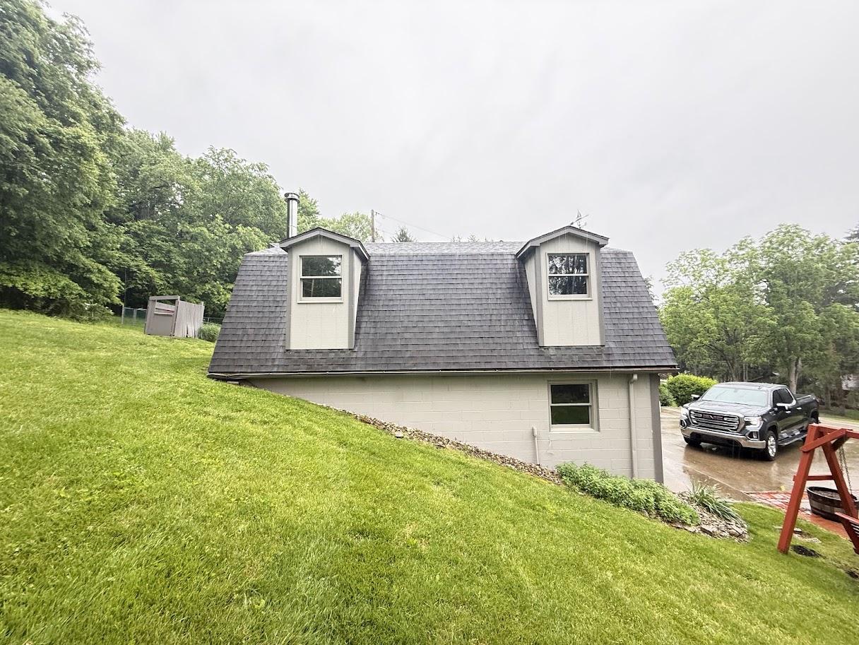 After image of the same house with a brand new, dark gray shingle roof.