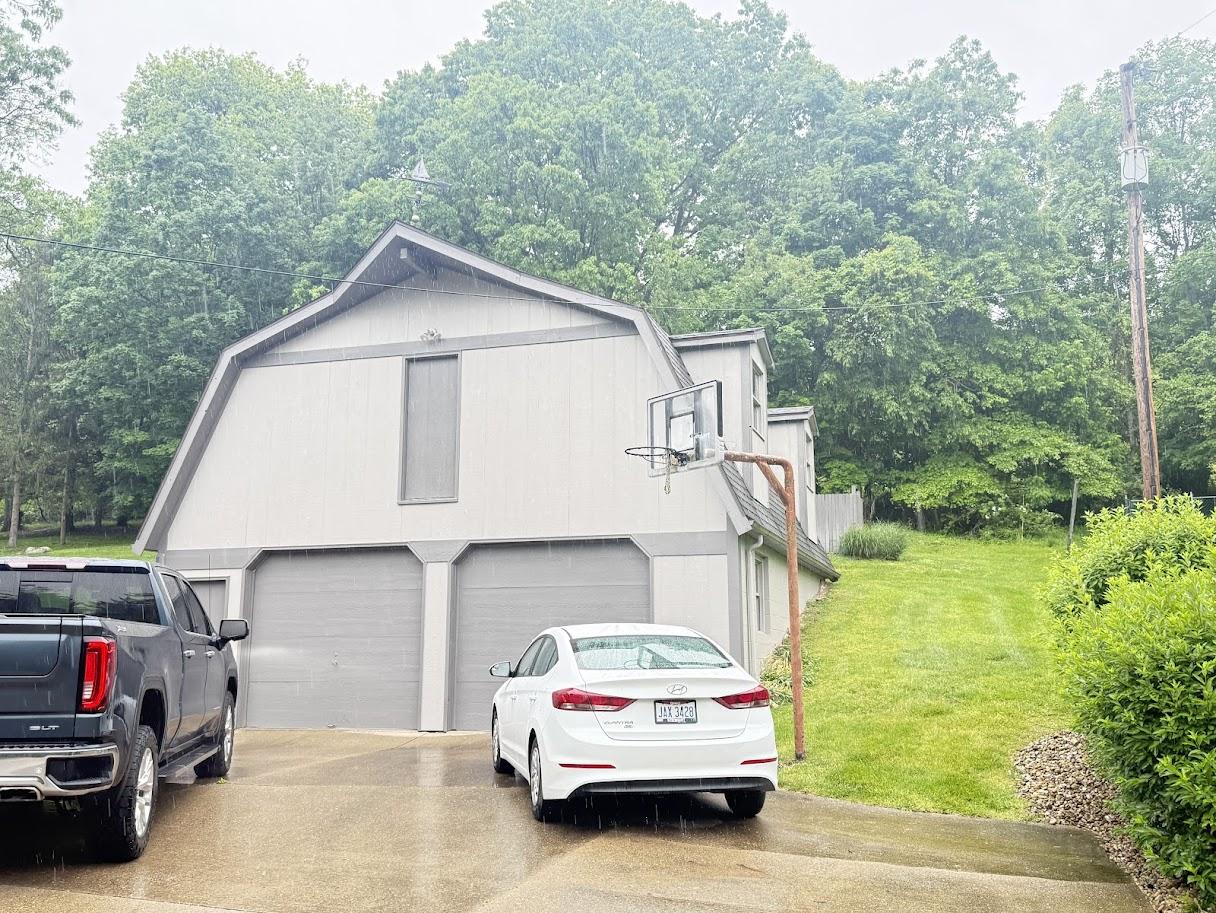 Before image of the house with an older, lighter gray/brown roof showing signs of wear.