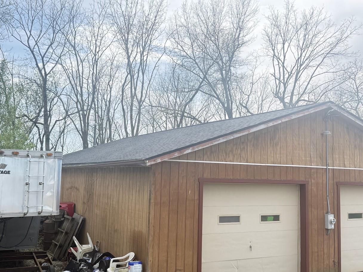 Before image of the house with an older, lighter gray/brown roof showing signs of wear.