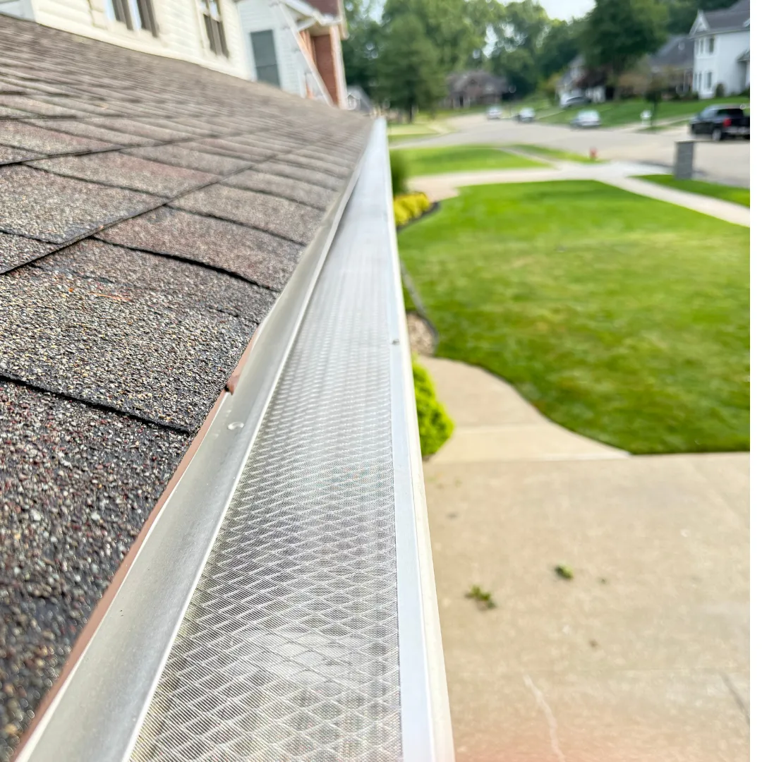 After image of the same house with a brand new, dark gray shingle roof.