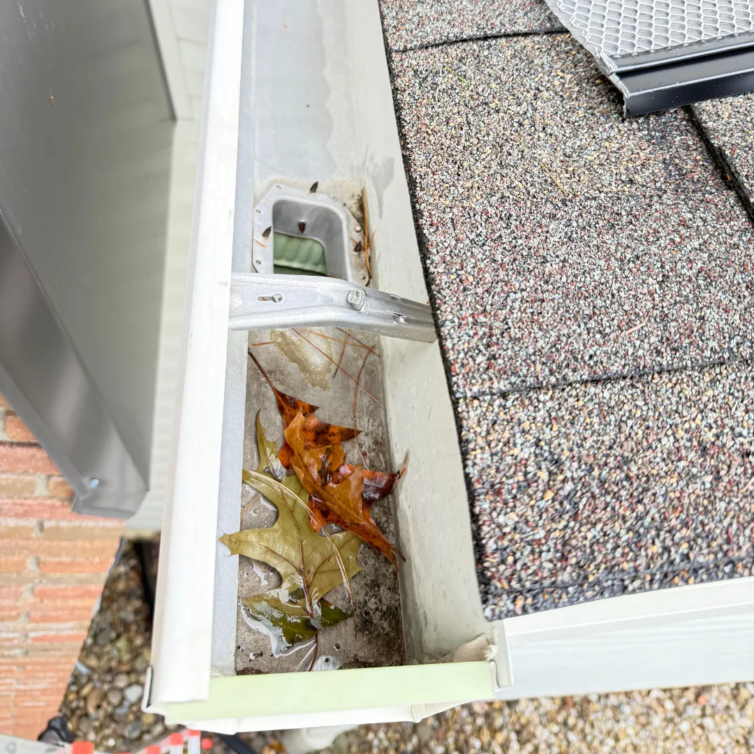 Before image of the house with an older, lighter gray/brown roof showing signs of wear.