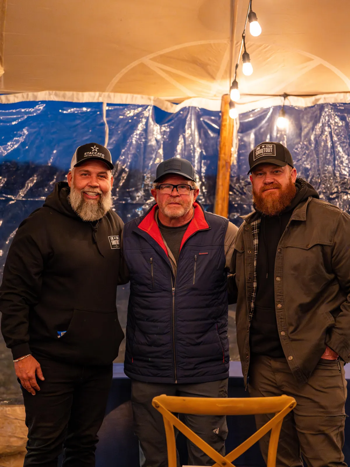 three men standing together under a tent