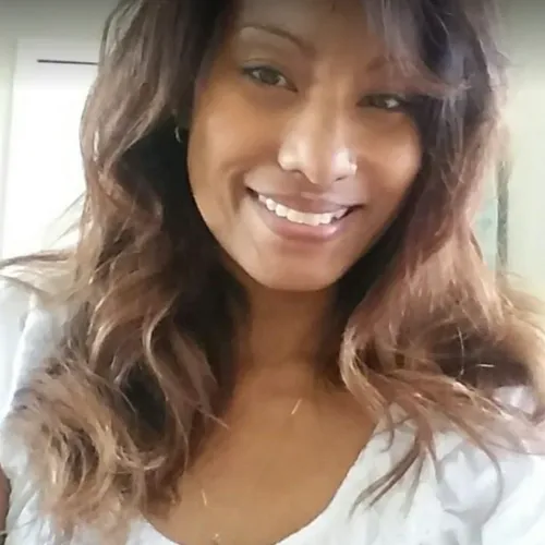 Image of Kimberly Boler, a skilled massage therapist at the clinic, smiling warmly at the camera. She is an African American woman with her hair gently falling across her face, conveying a friendly and welcoming presence.