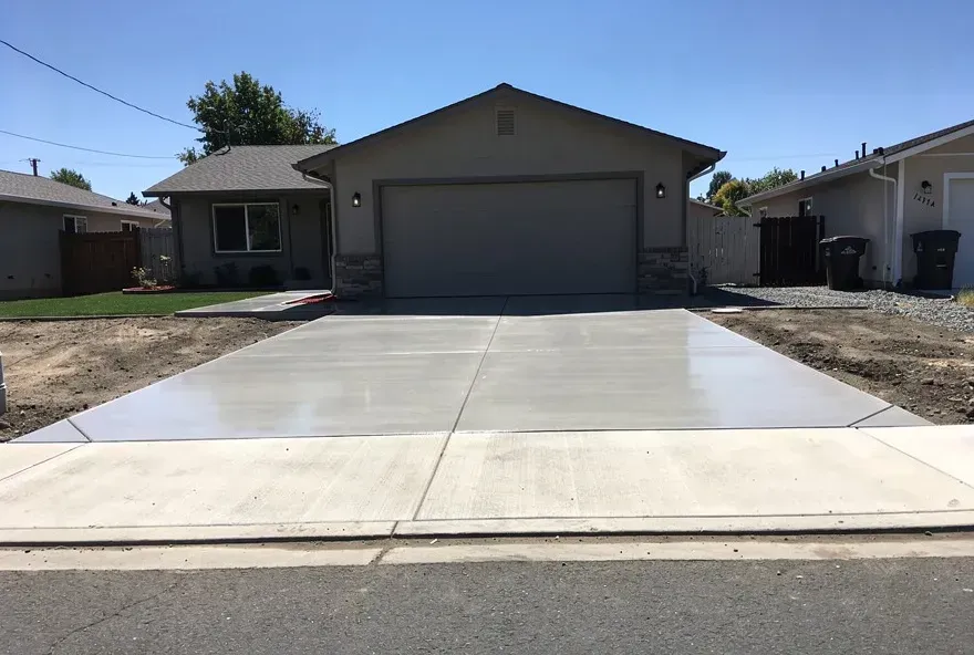 Freshly finished concrete driveway attached to garage door of modest home in Red Bluff California