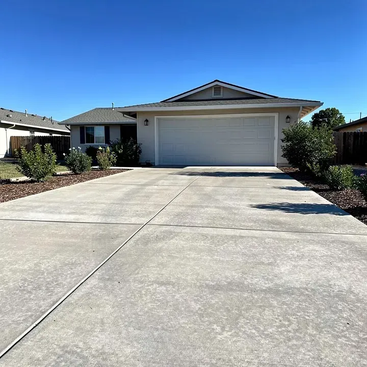 Clean settled concrete driveway attached to garage door of modest home on a sunny day in Red Bluff California