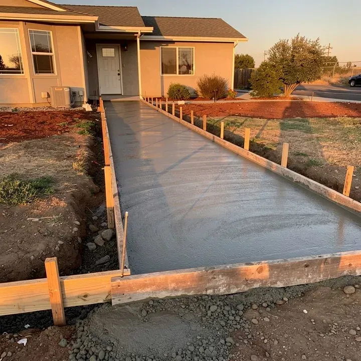 Freshly poured concrete sidewalk in progress within wood forms at a residential property in Red Bluff California during evening light