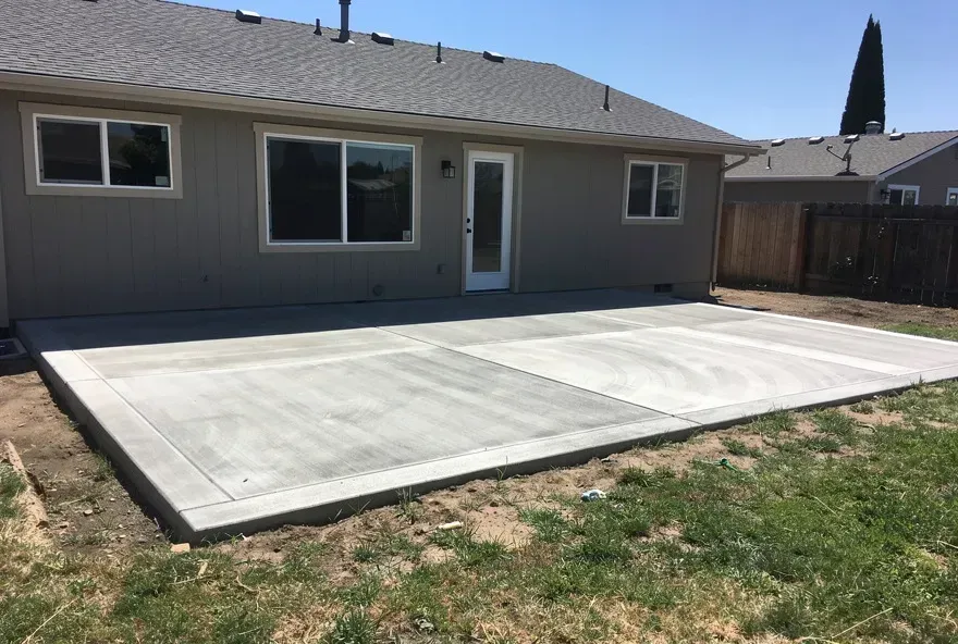 Freshly finished concrete patio attached to the back of a modest home in Red Bluff California