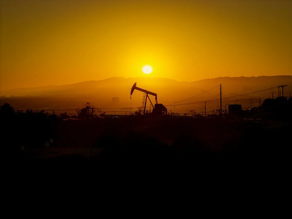 Oil pump jack silhouetted against a hazy sunset, symbolizing the energy price spike feeding into the Fed's inflation outlook