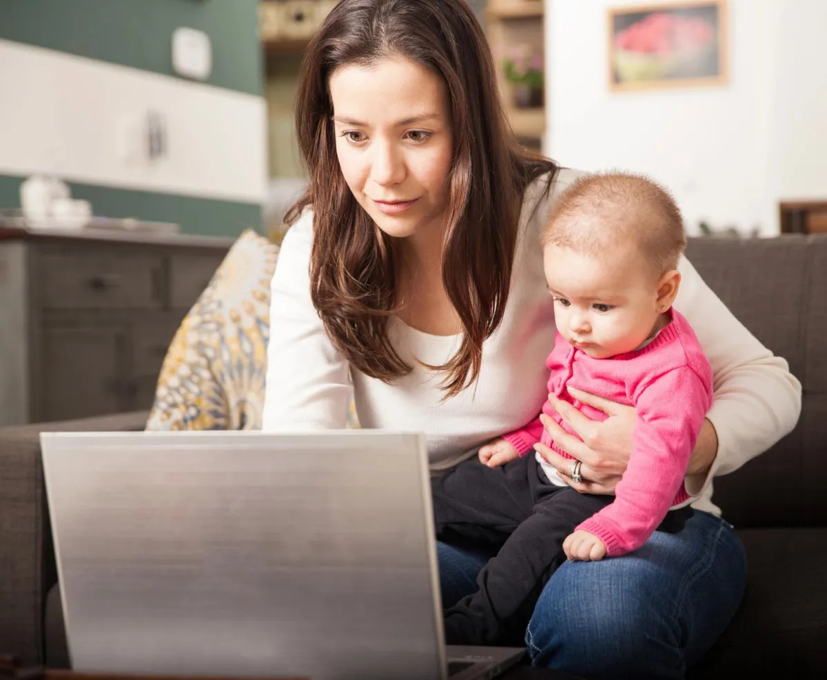 Mom looking at laptop computer with an infant on her lap