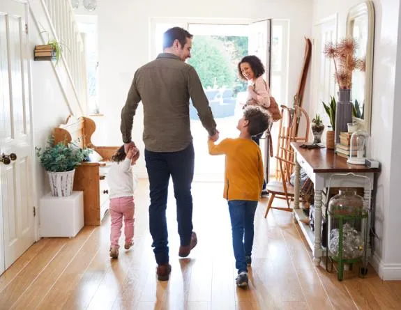 View of a foyer with the father holding boy's & girl's hands with mother in front, leaving the house