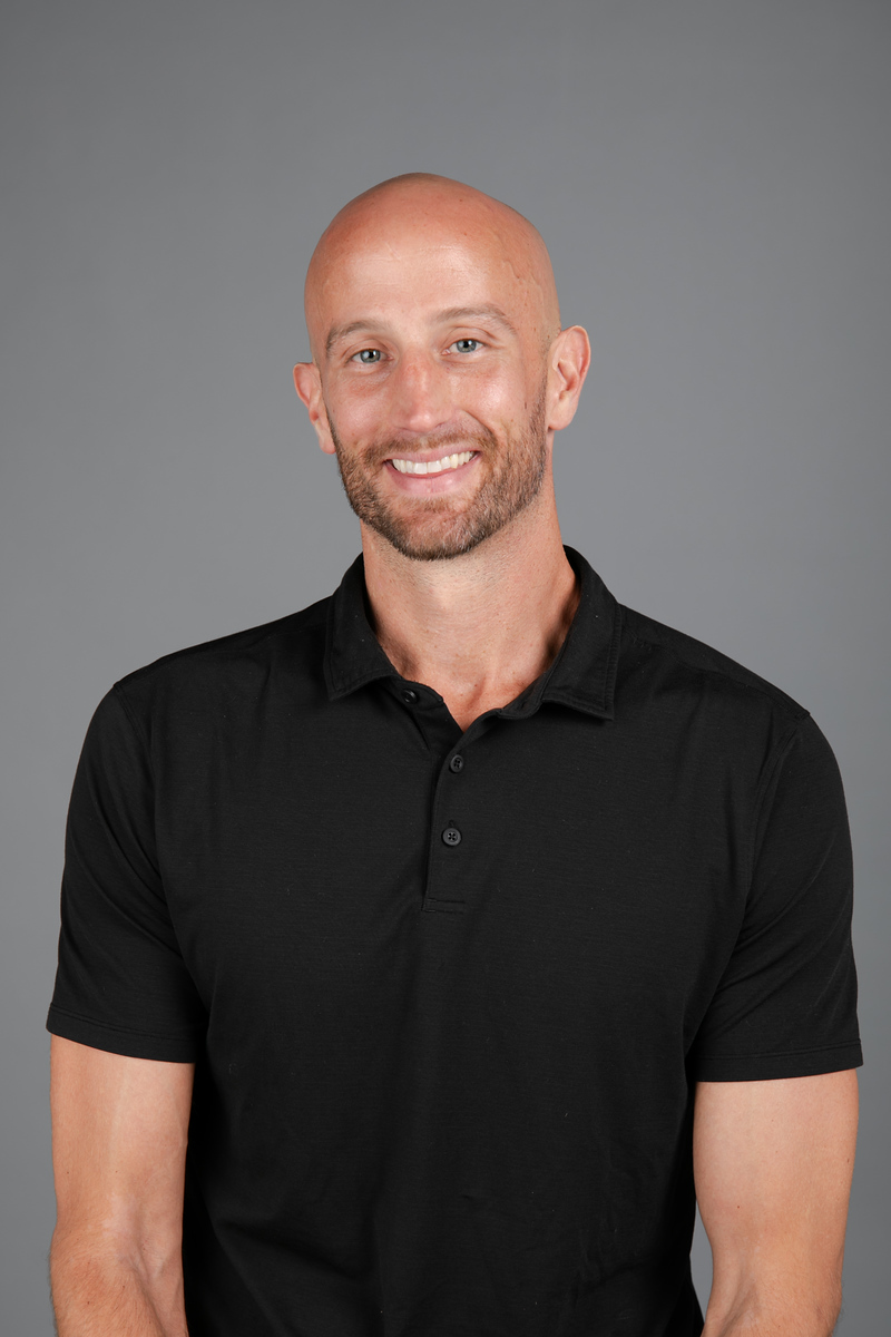 Man exercising on a leg press machine with a female trainer assisting, demonstrating personalized exercise therapy at ZOVA Chiropractic Rehab Center.