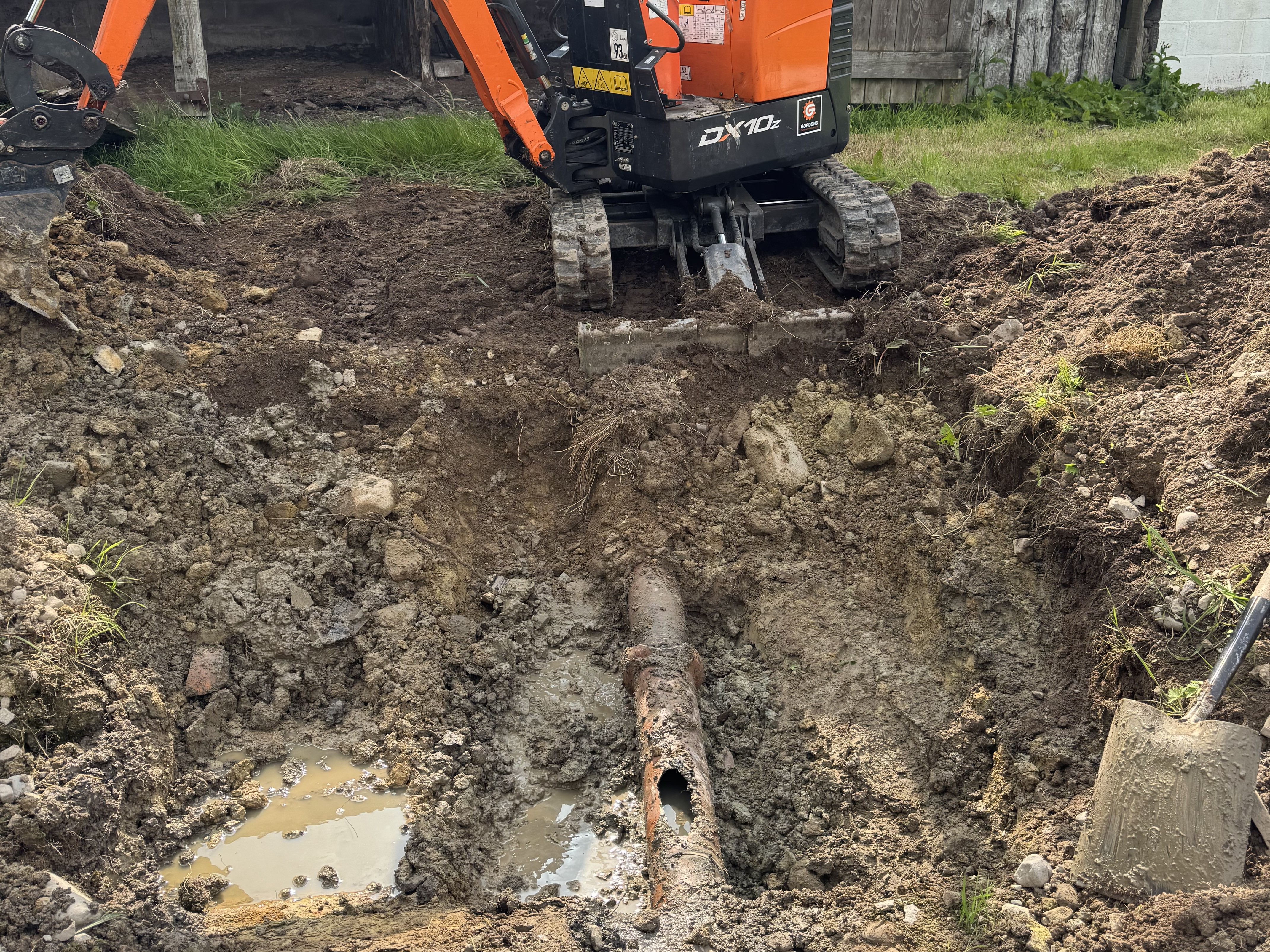 JF Groundworks excavator exposing damaged sewer line during drainage repair works in Dumfries and Galloway