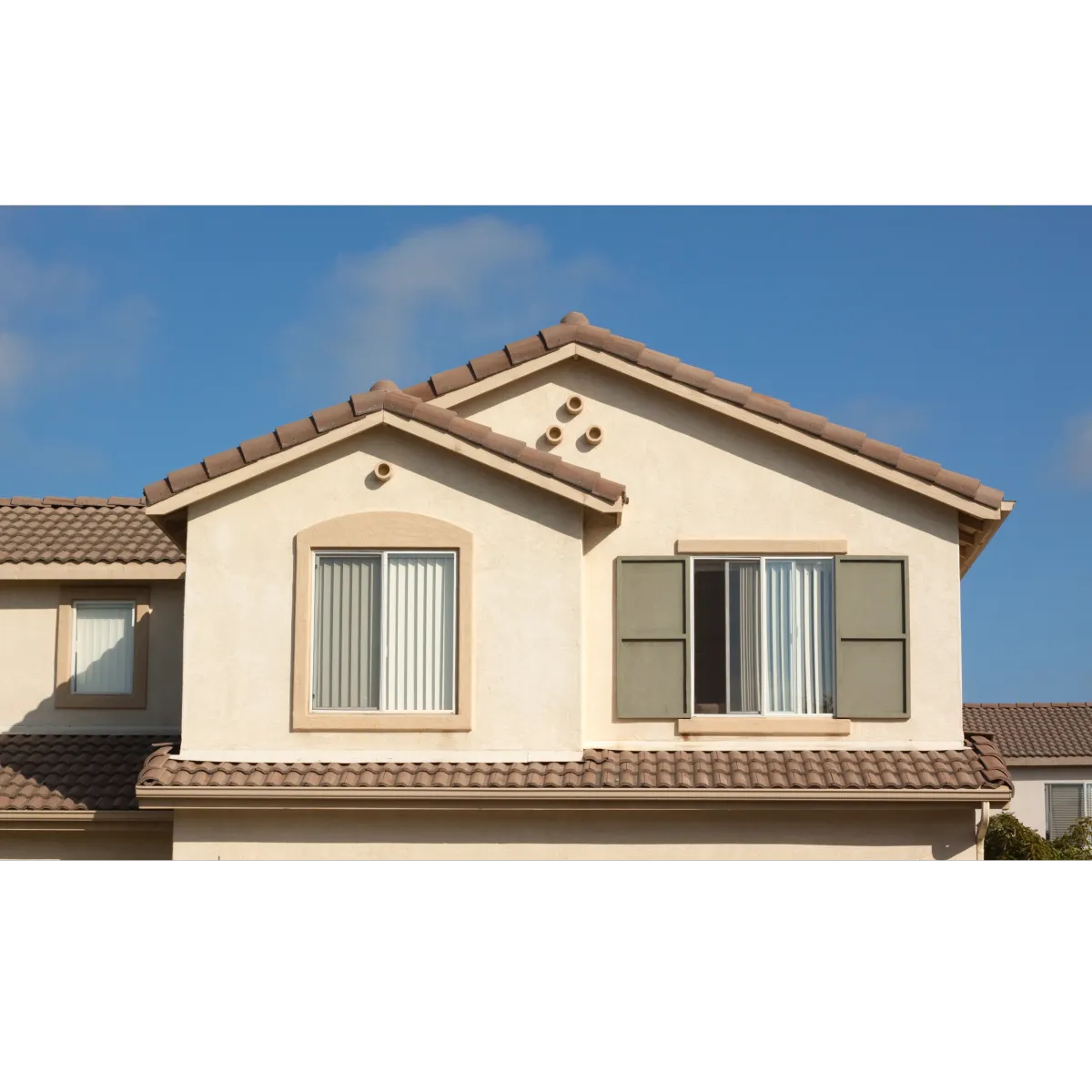 Tan stucco with brown roof and three windows