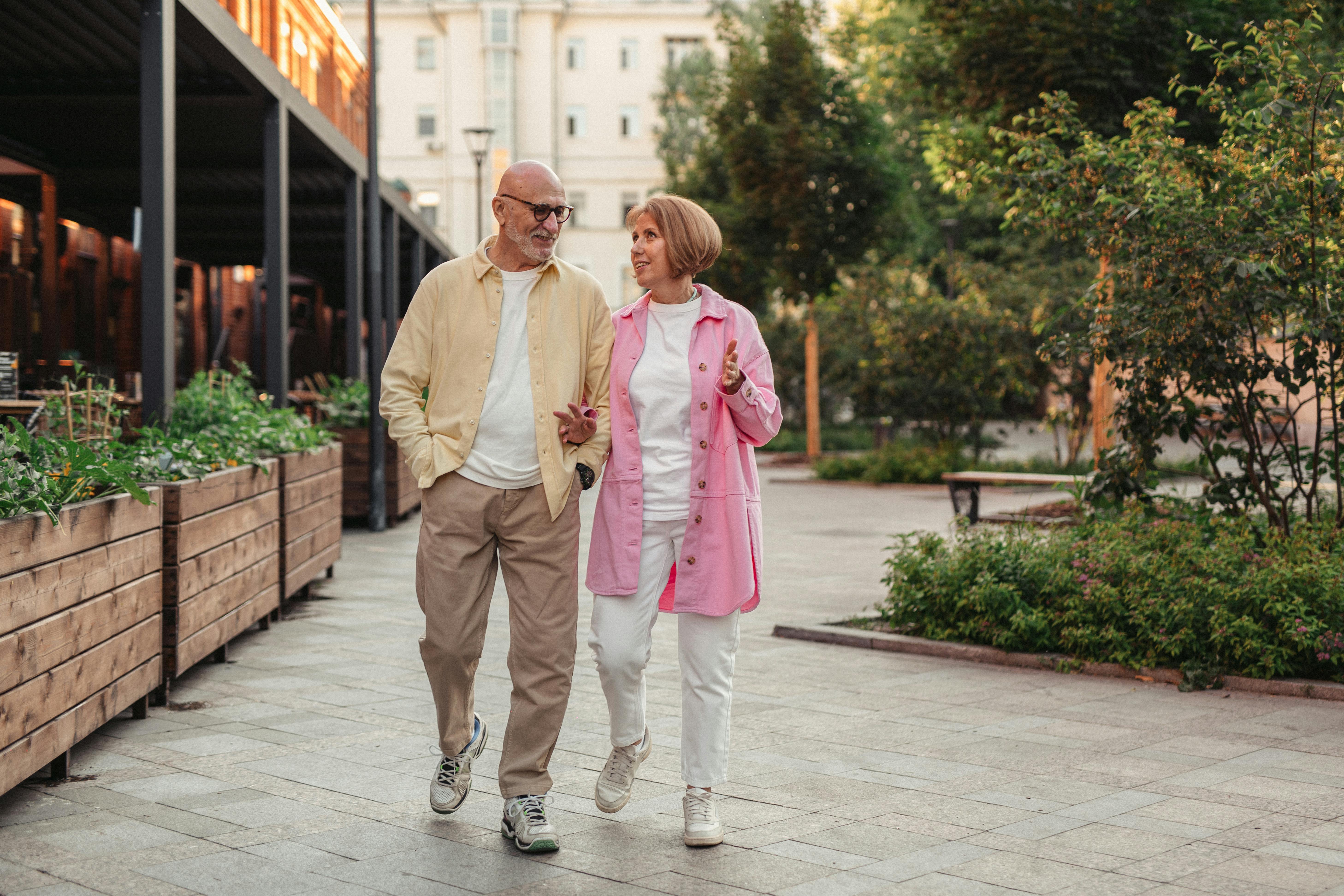 an older woman and man walking side by side with arms locked and smiling