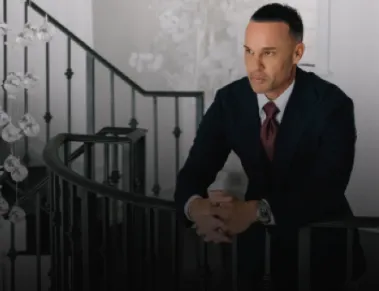 Marc Effron wearing a suit and sitting on the stairs.