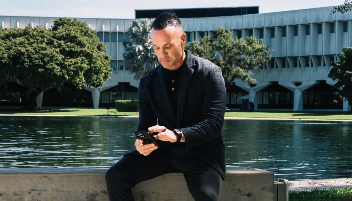 Marc Effron sitting by the water in front of a building and finding ways to find validation.