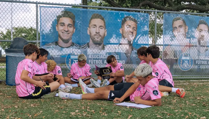 Young athletes sitting on the end of a field working in their D3 Youth Performance Workbooks.