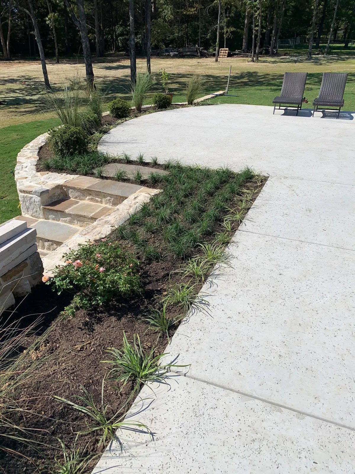 Stone seating wall and new plantings along a concrete patio overlooking the lake
