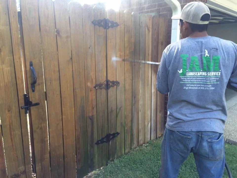 JAM Tyler Landscape crew member Pressure Washng a fence to bring back it's natural beauty
