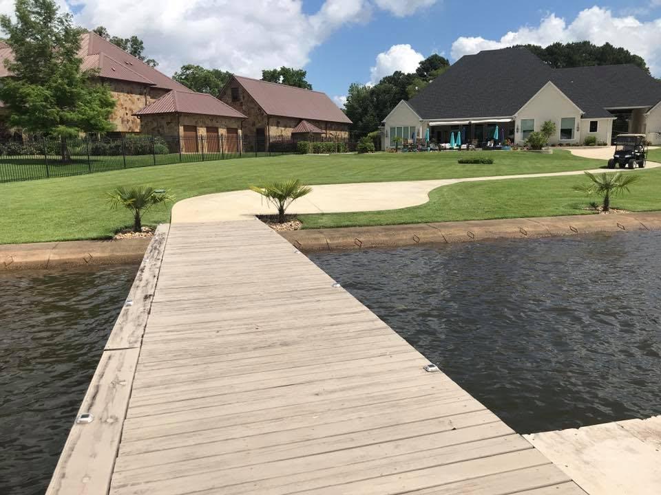 Wooden dock over a pond with a manicured lakeside lawn in East Texas