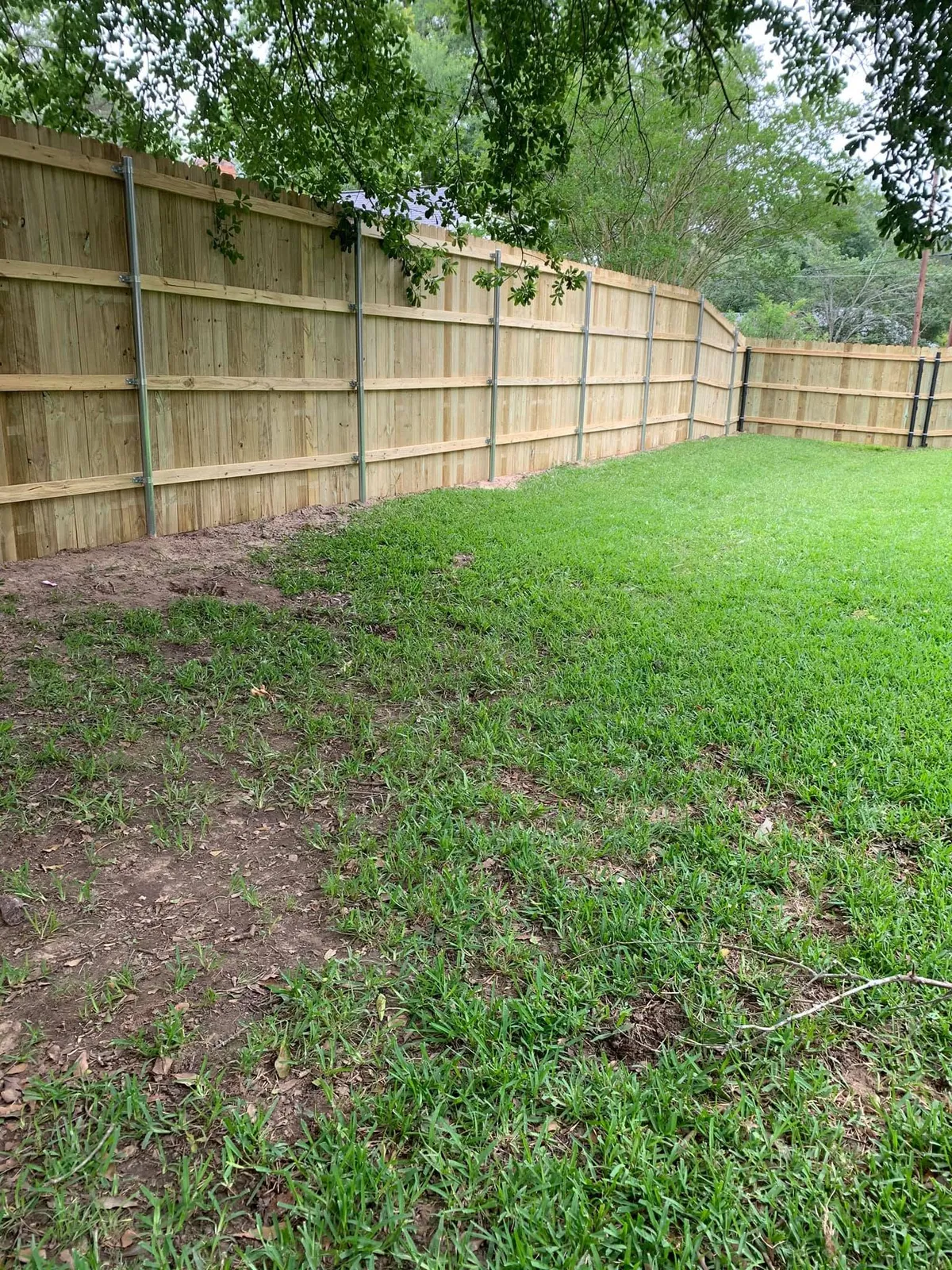 New wood privacy fence with steel posts installed along a back yard in Tyler TX