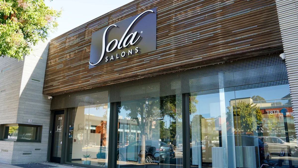 woman signing on white printer paper beside woman about to touch the documents