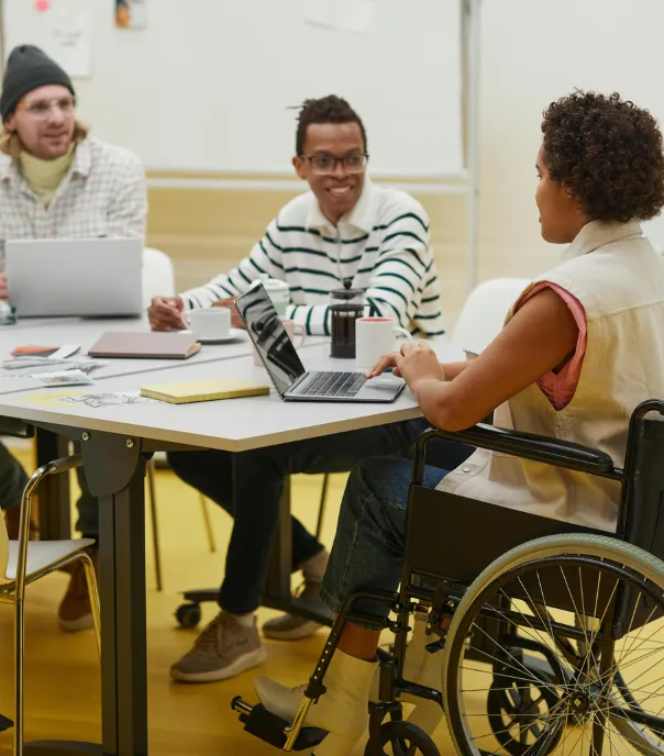 Person using a wheelchair collaborating with colleagues during an inclusive team meeting.