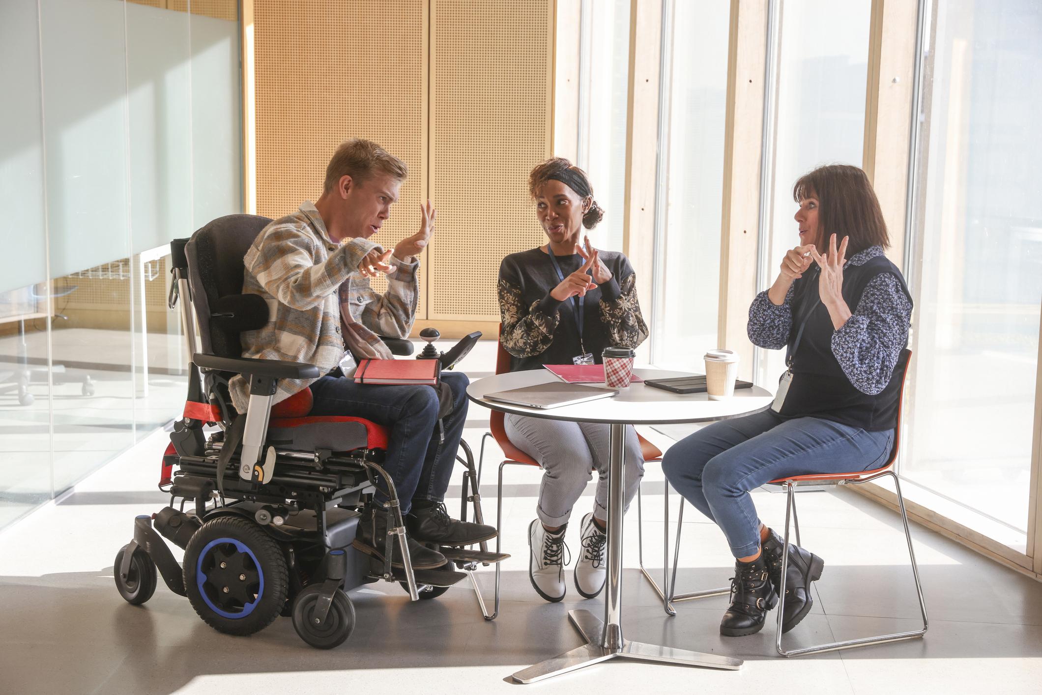 Person using a powered wheelchair participating in an inclusive team meeting.