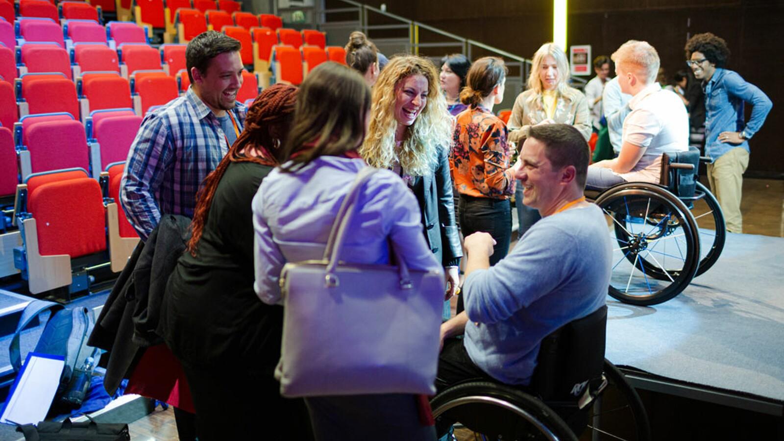 People with and without disabilities participating in an inclusive workshop and group discussion in an auditorium.