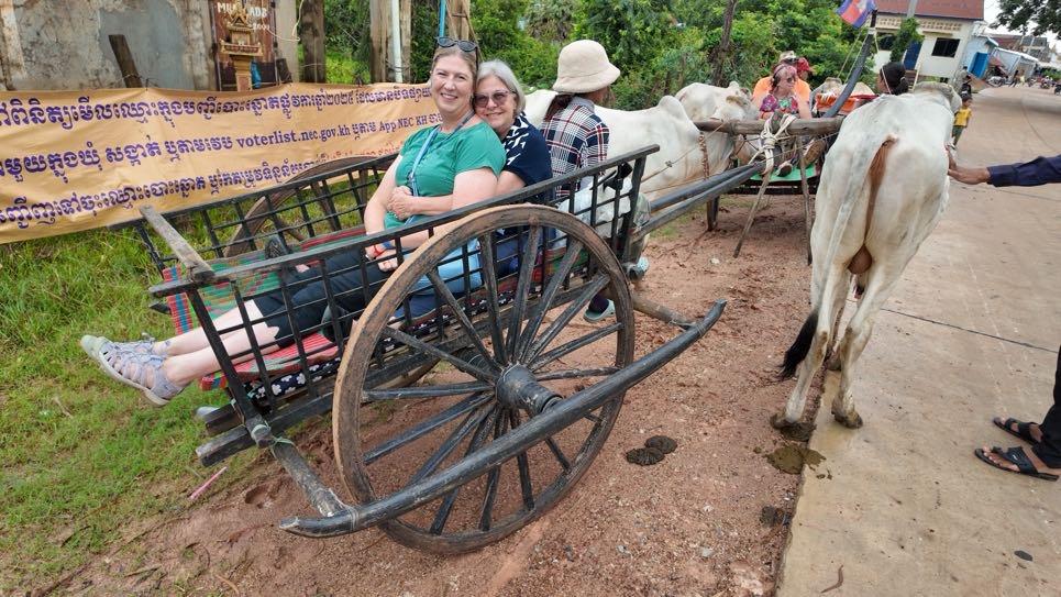 Two women sit hugging in an ox cart in Vietnam 