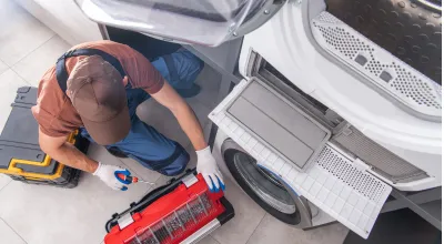 Expert technician fixing a residential dryer that is not heating or tumbling.