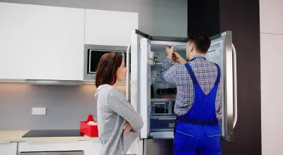 Residential refrigerator being serviced by a technician to resolve cooling issues.