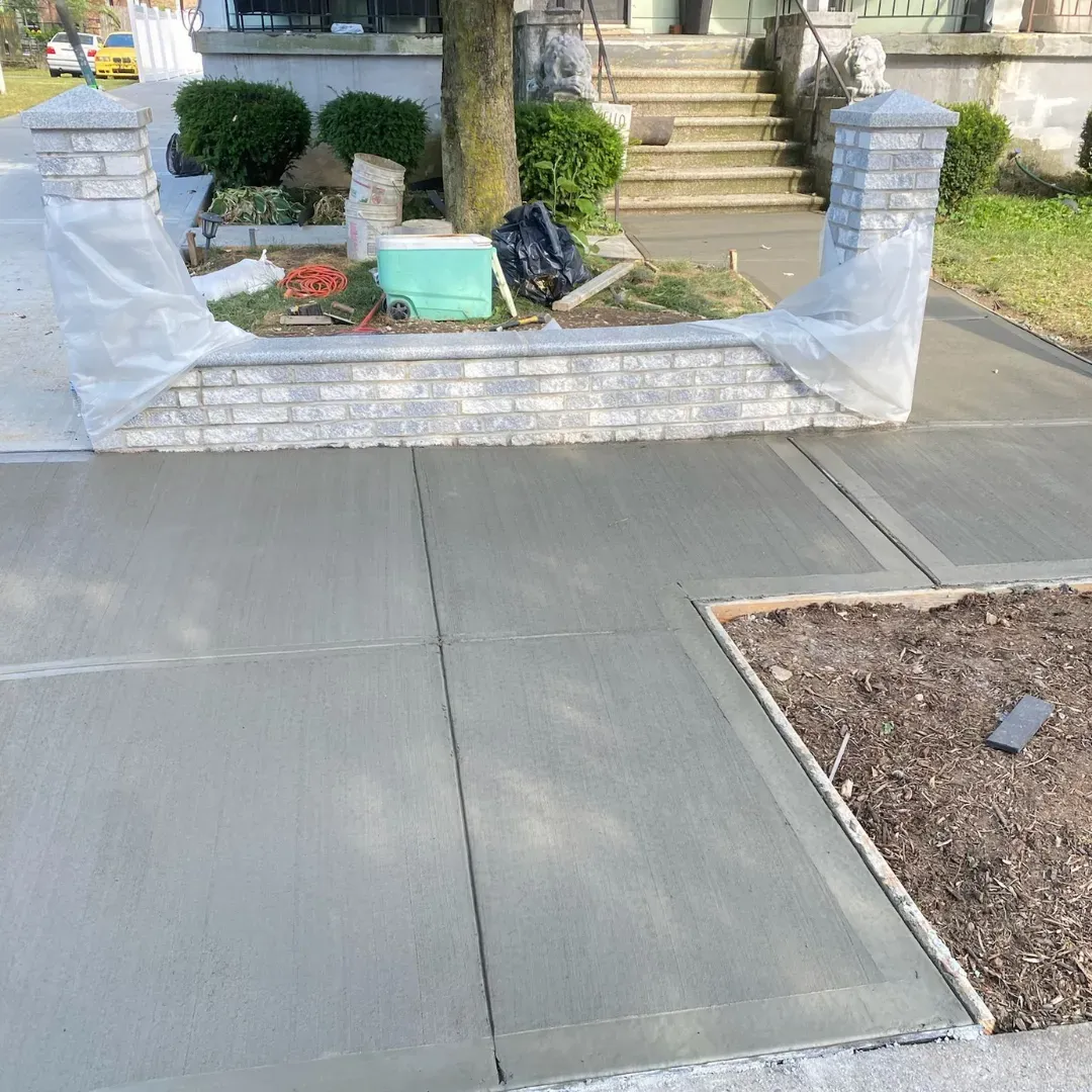 Fresh concrete sidewalk repair and pouring in Queens, New York. Exterior improvement project with new masonry finishes by Blue Empire