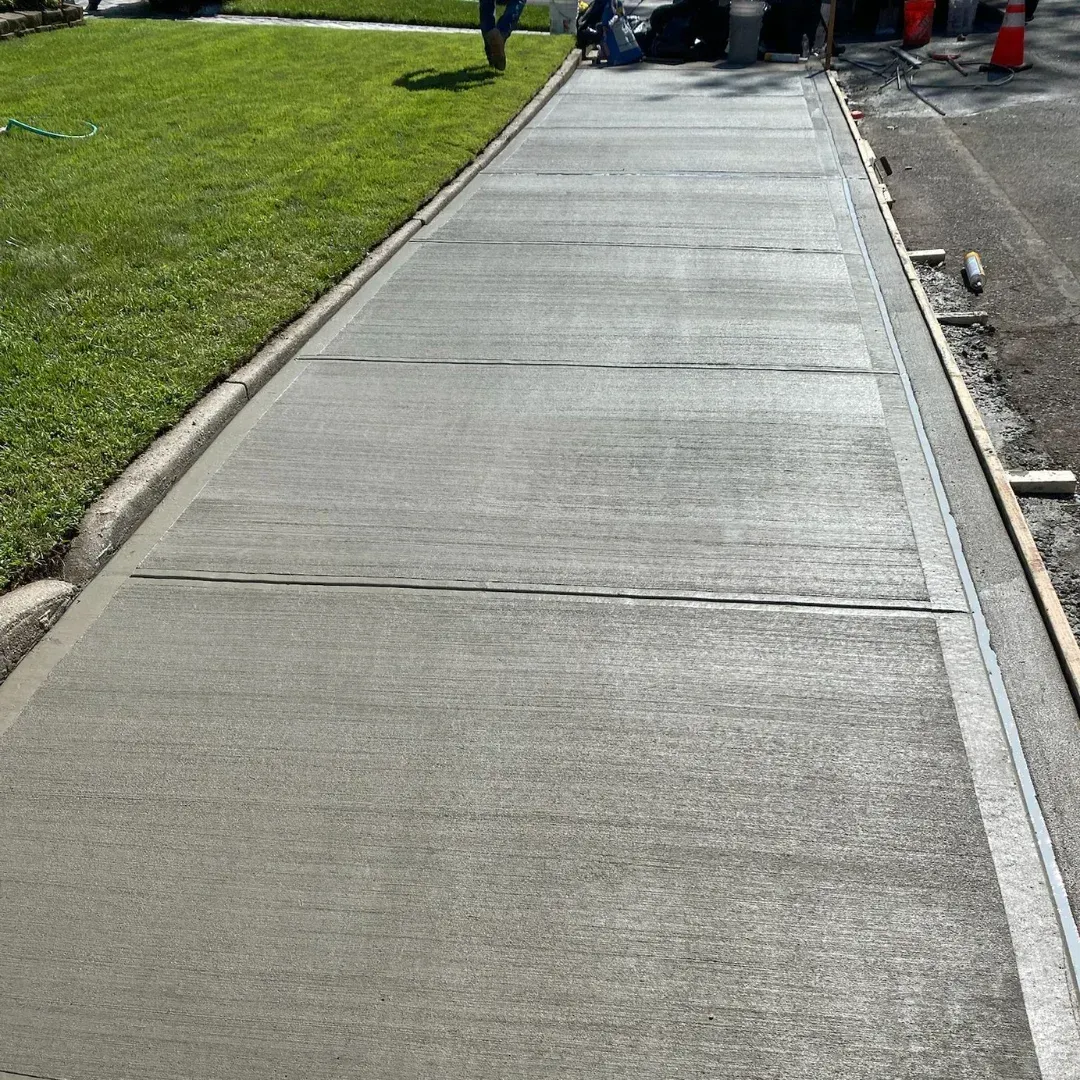 A newly constructed broom finish concrete driveway is visible at a residential property in Queens, New York.